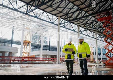 Construction managers using digital tablet on site, reviewing project plans. Stock Photo