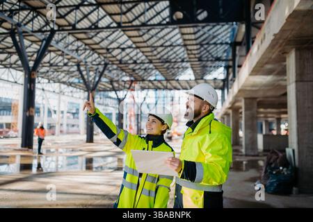 Engineers discussing construction plans using a tablet on site. Stock Photo