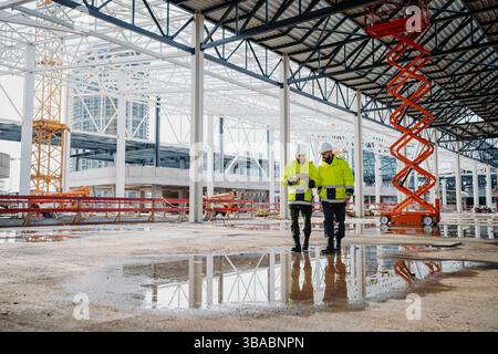 Engineers discussing construction plans using a tablet on site. Stock Photo