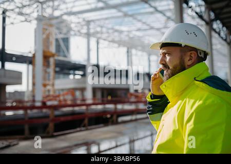 Portrait of construction foreman making phone call in modern building site. Stock Photo