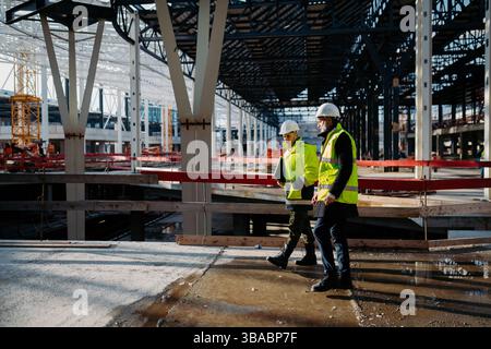 Construction managers using digital tablet on site, reviewing project plans. Stock Photo
