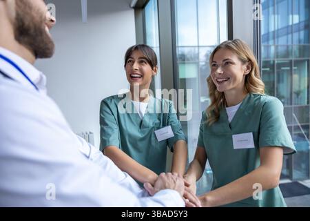 Group of doctors holding hands together and looking positive and smiling Stock Photo