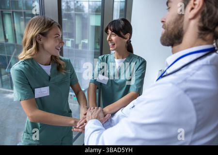 Group of doctors holding hands together and looking positive and smiling Stock Photo