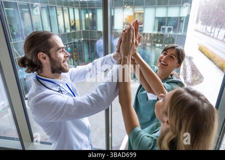 Group of doctors holding hands together and looking positive and smiling Stock Photo