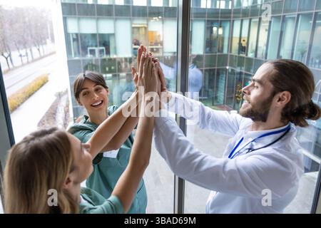 Group of doctors holding hands together and looking positive and smiling Stock Photo