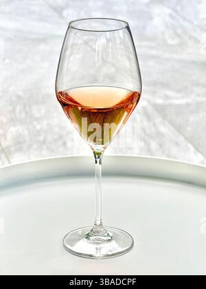 Glass of rose wine on a white circular table isolated against a plain background. No people. Stock Photo
