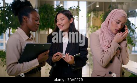 Diverse multiethnic girls three women female teamwork at office African Asian businesswomen business partners three happy smiling cheerful happy co Stock Photo