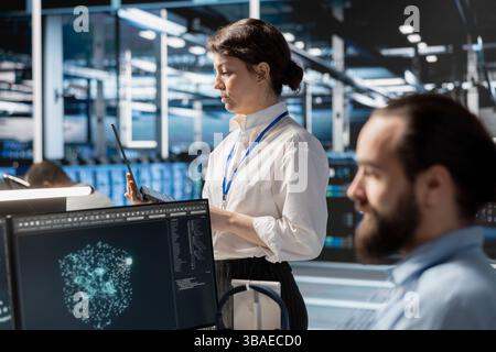 Admins using computer in data center office, managing server virtualization, running scripts. IT employees using programming language on PC in server room, finetuning network protocols Stock Photo