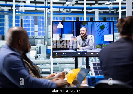 Investors evaluating solar panels manufacturing plant production during internet videocall before investing. Shareholders doing remote videoconference with managers to ask technical questions Stock Photo