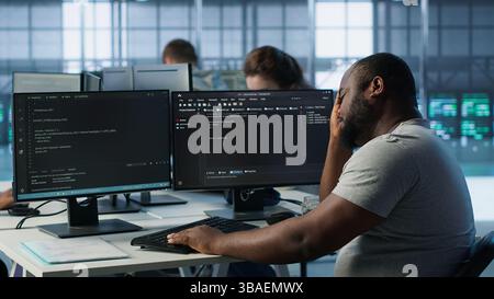 System admin feeling ill, having fever while working in computer network security data center. Sick worker suffering headache while monitoring energy consumption across server racks, camera A Stock Photo