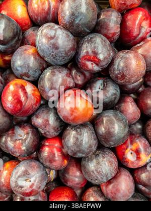 Ripe plums displayed on greengrocer's counter, top view Stock Photo