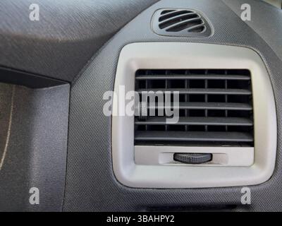 Detailed close-up of a car air vent showing the control knob and vent slats. Stock Photo