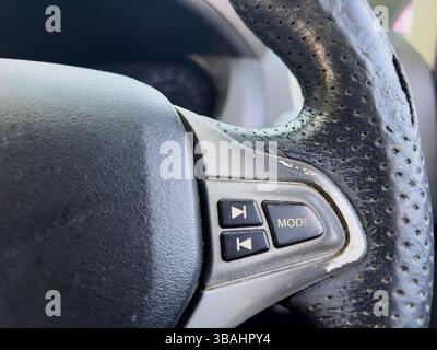 Detailed of a car steering wheel showing control buttons for mode and track selection. Stock Photo