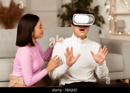 Millennial Couple Using Virtual Reality Glasses Playing Game At Home Stock Photo