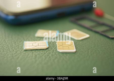 Different sizes of SIM cards next to a smartphone on green background Stock Photo