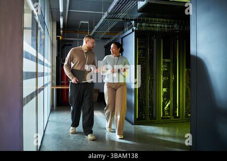 Colleagues Discussing Work while Walking in Server Room Stock Photo