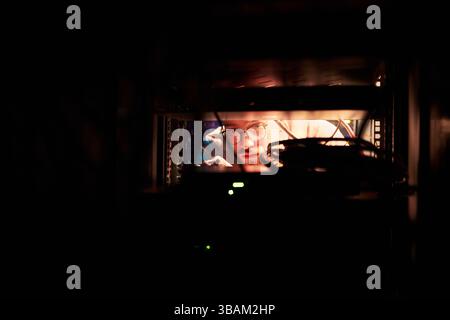 Man Working Behind Electronic Equipment Rack Focused Stock Photo
