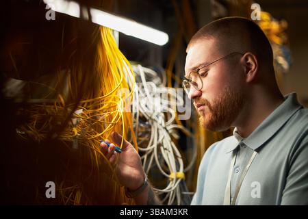 Man Working with Network Cables and Electronic Devices Stock Photo