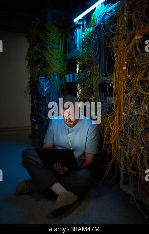 Technician Monitoring Network Cables in Server Room Stock Photo