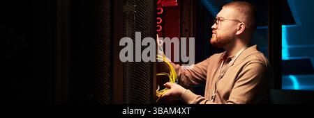 Technician Working in Data Center Fixing Network Cables Stock Photo