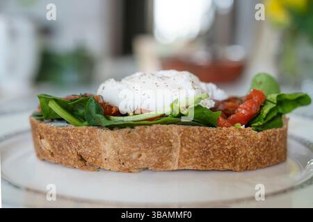 a delicious breakfast poached egg on a slice of ciabatta with spinach and pieces of red salted fish Stock Photo