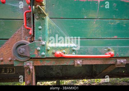 The train is old and rusty, with green paint on the side. The handles on the train are red, and they are located on the side of the train. The train a Stock Photo