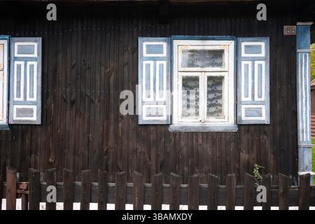 A house with blue shutters and a white window. The shutters are open and the window is closed Stock Photo