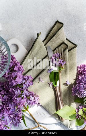 Overhead view of a springtime cutlery setting with purple lilac flowers on a table Stock Photo