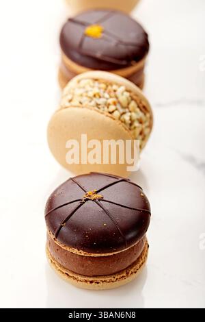 Close-up of a row of assorted Chocolate and Nut Macarons (french macaroons) on a marble table Stock Photo