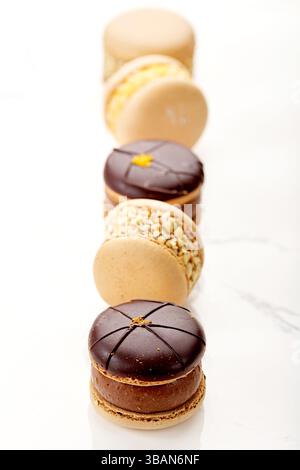 Close-up of a row of assorted Chocolate and Nut Macarons (french macaroons) on a marble table Stock Photo
