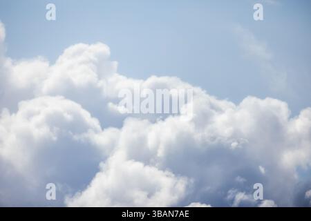 Soft, fluffy white clouds float in a serene bright blue sky exuding tranquility and peace. Background photo texture Stock Photo
