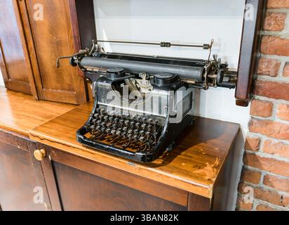 Antique typewriter on an old wooden tabletop against a brick wall. Stock Photo