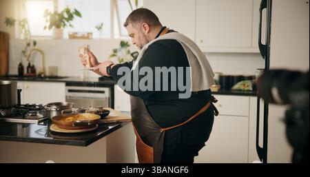 Man, chef and recording in kitchen with food, dinner or recipe online for content creation. Camera, cooking and influencer person with equipment for Stock Photo