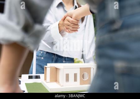 Sustainability focused engineers celebrating success with architectural model Stock Photo