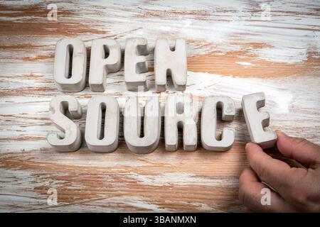 Open Source. Concrete alphabet letters on a light painted wood texture background. Stock Photo