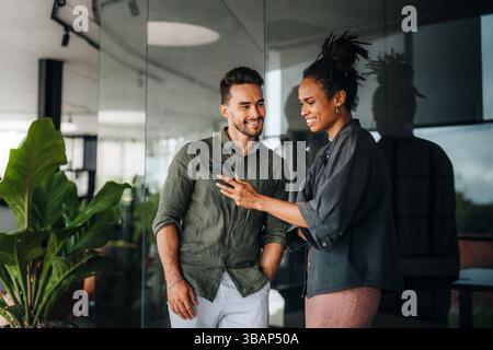 Diverse colleagues using smartphone together, discussing online project and having fun in office Stock Photo