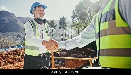 Construction worker, partnership and people shaking hands outdoor for agreement on development deal. Mature man, builder or engineers together for Stock Photo