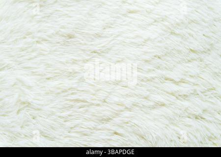 A close-up shot shows a fluffy, white faux sheepskin rug. The soft, textured fibers create a dense and inviting surface. Stock Photo