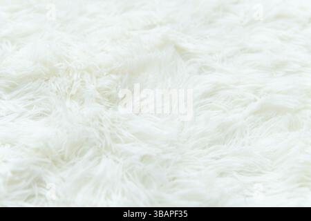 A close-up shot shows a fluffy, white faux sheepskin rug. The soft, textured fibers create a dense and inviting surface. Stock Photo