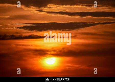 Sunset in the sky in red colors. Orange sky with clouds in the evening. Nature background. Stock Photo
