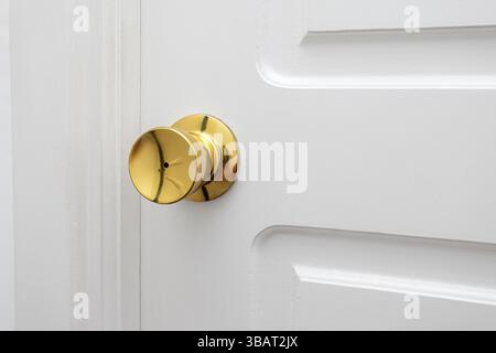 Golden doorknob mounted on a white wooden door, representing modern interior design and elegance Stock Photo