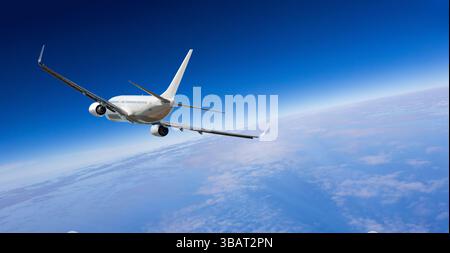 White passenger airplane flying high above the earth and clouds on beautiful deep blue sky Stock Photo