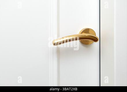 Close-up of a golden door handle on a white door, symbolizing luxury and sophistication Stock Photo
