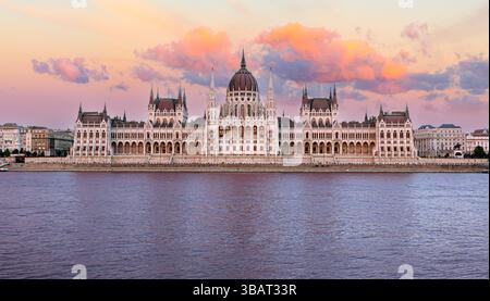 Hungarian parliament building, also known as országház reflecting on danube river at sunset with colorful clouds in budapest, hungary Stock Photo