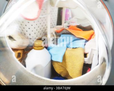 Laundry machine with clothes and cleaning product. Represents chores, routine, domesticity, and cleanliness. Use for articles on home life, cleaning, Stock Photo