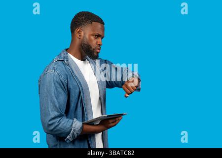 Young entrepreneur checking the time while holding a tablet, managing his busy schedule Stock Photo
