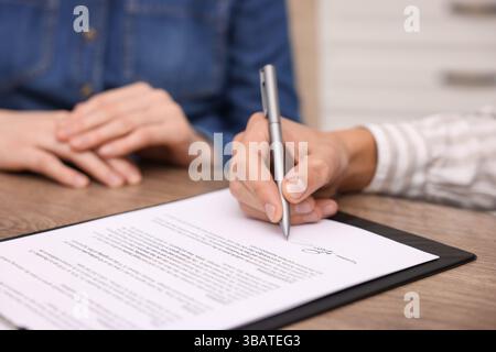 Man putting signature on document at table, closeup Stock Photo