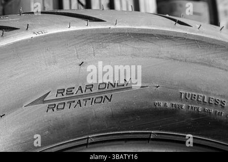 Close-up of the side of a new road motorcycle rear tire with the direction of rotation indicated, big motorbike wide rear tire Stock Photo