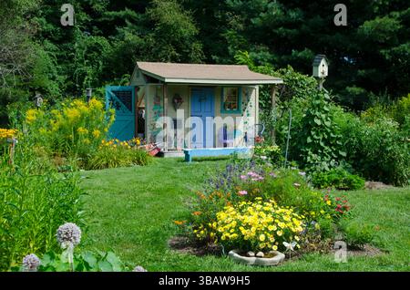 Cute Painted shed in children's garden for tool storage in a blooming summer flowers at the community Garden, Yarmouth ME, USA Stock Photo