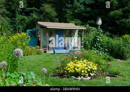 Cute Painted shed in children's garden for tool storage in a blooming summer flowers at the community Garden, Yarmouth ME, USA Stock Photo